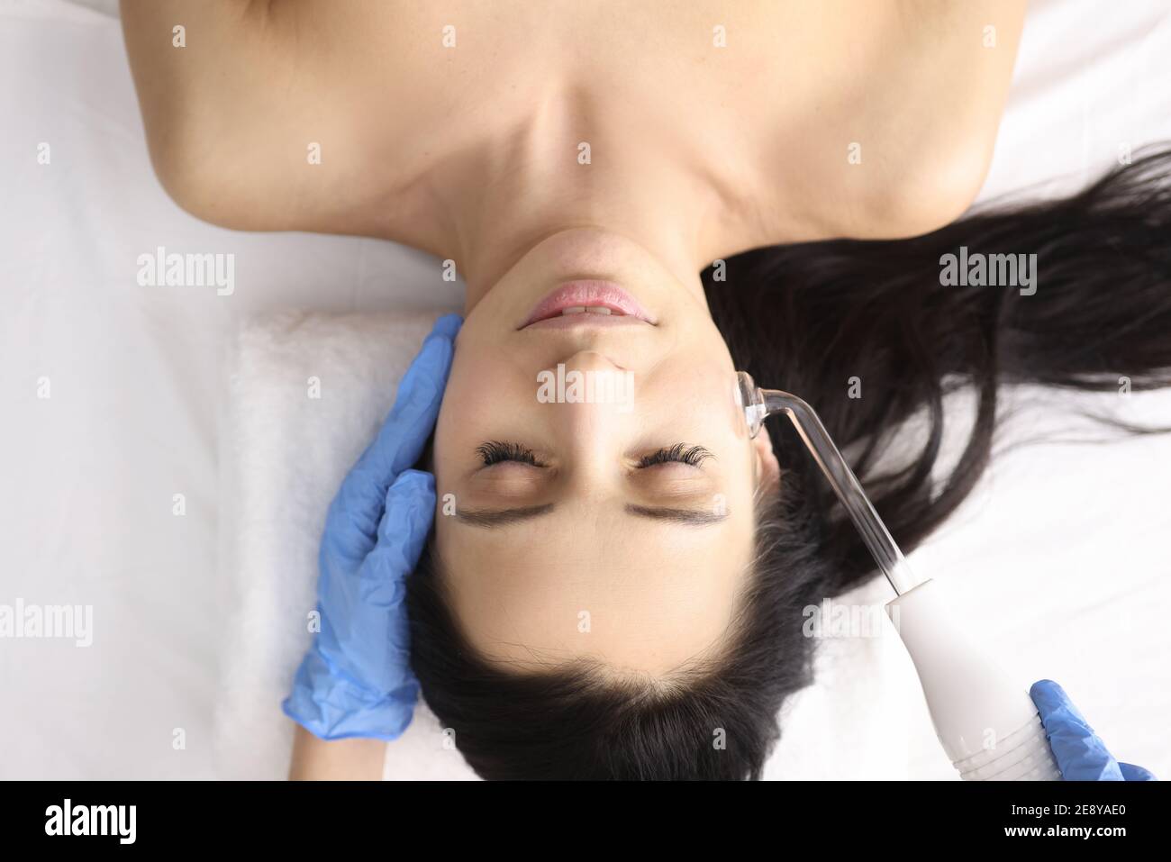 Dottore in guanti facendo massaggio viso con darsonval Foto Stock
