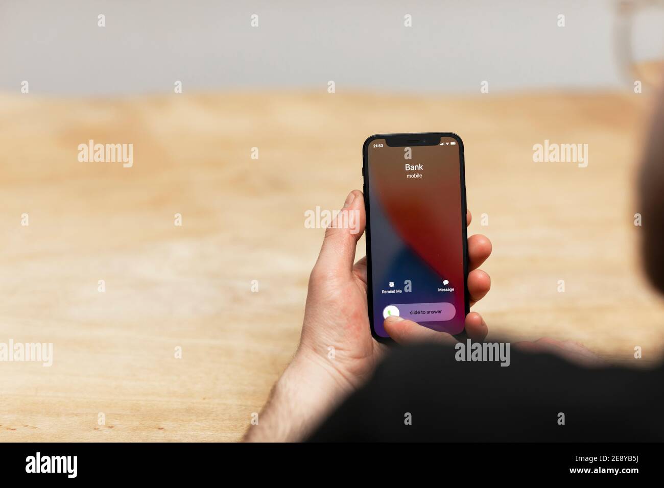 Attacco di spoofing da parte di uno scammer. Un uomo che risponde al suo telefono cellulare mentre la sua banca sta chiamando. Falso numero di spoofing del criminale che tenta di fare un phishing a. Foto Stock