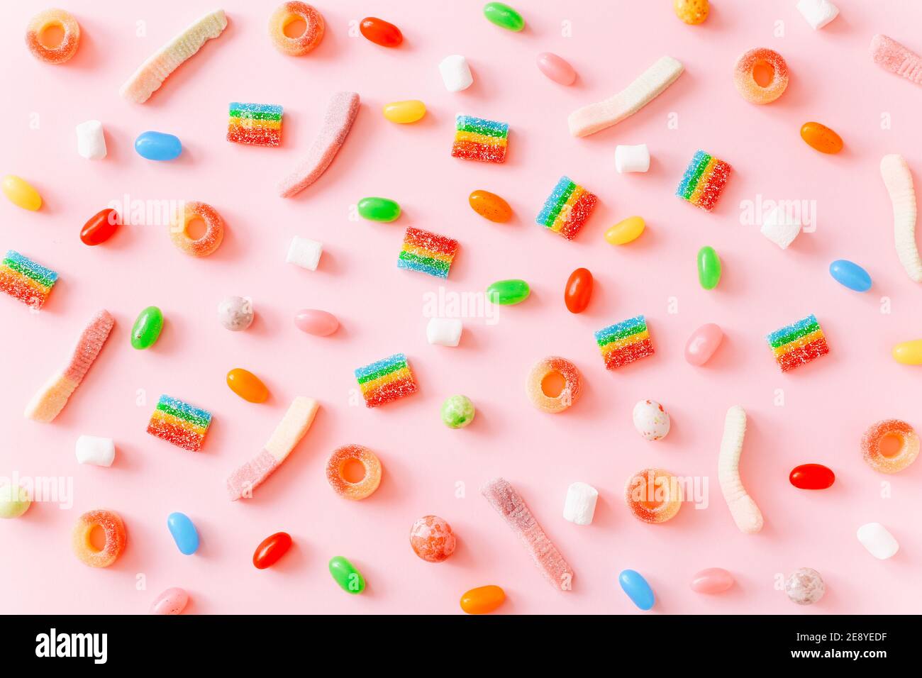 Arcobaleno succosa gummy candie sfondo. Modello da dolci di gelatina su sfondo rosa Foto Stock