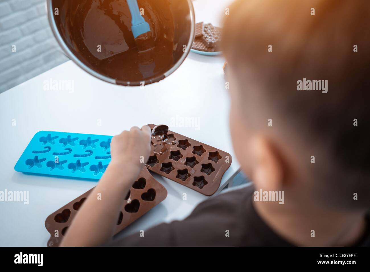 closeup di ragazzo che fa caramelle al cioccolato o dolci a. casa cucina moderna Foto Stock