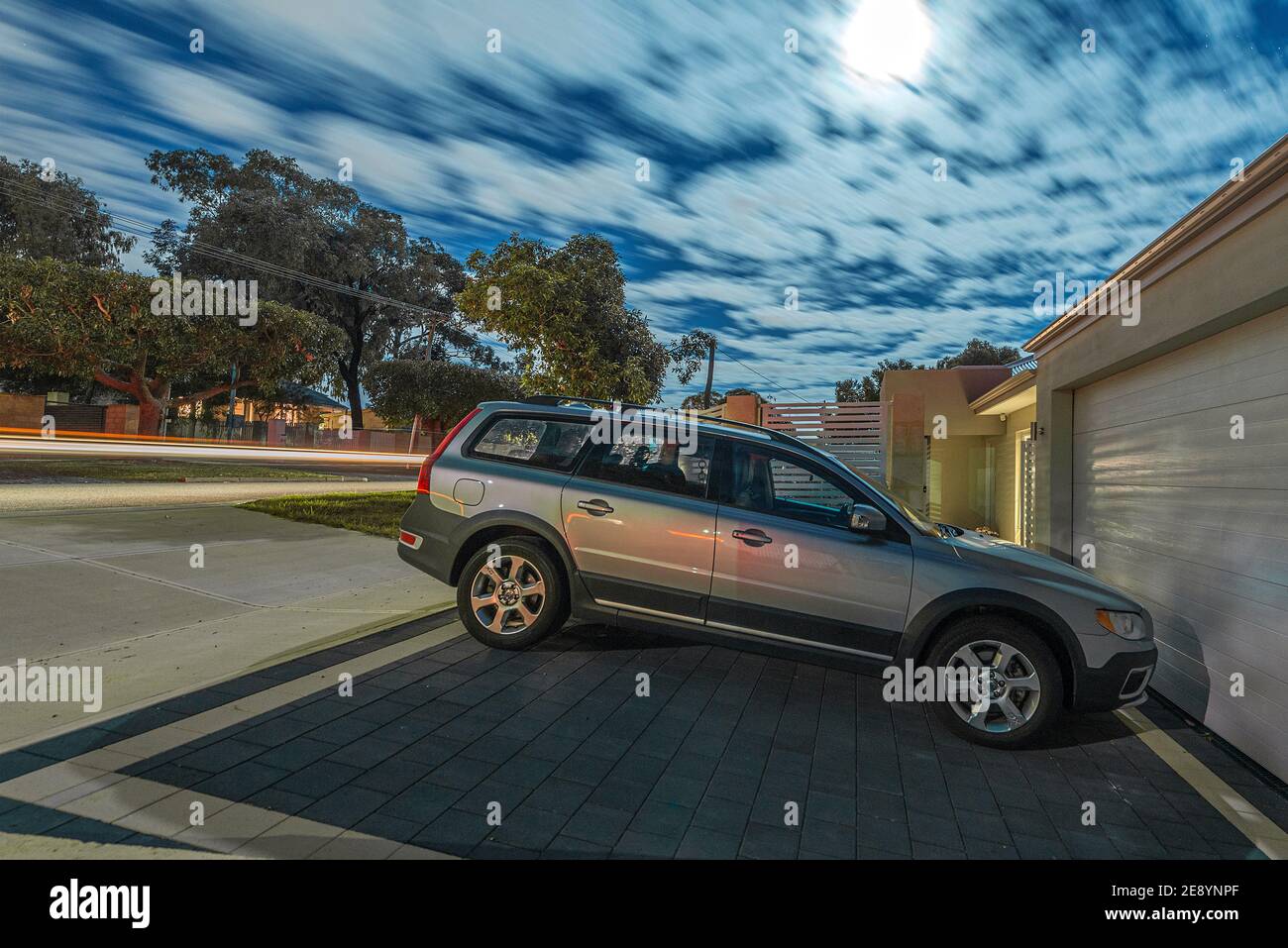 Un'esposizione notturna al chiaro di luna di una moderna strada suburbana australiana, con un'auto Volvo in un vialetto. Foto Stock
