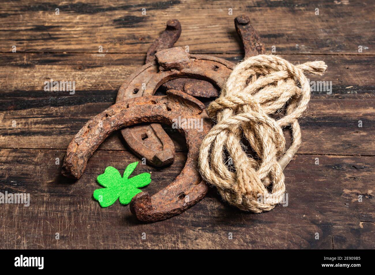 Ferro di cavallo, corda e foglia di trifoglio in feltro mal indossati. Simbolo di buona fortuna, concetto di giorno di San Patrizio. Vintage tavole di legno sfondo Foto Stock