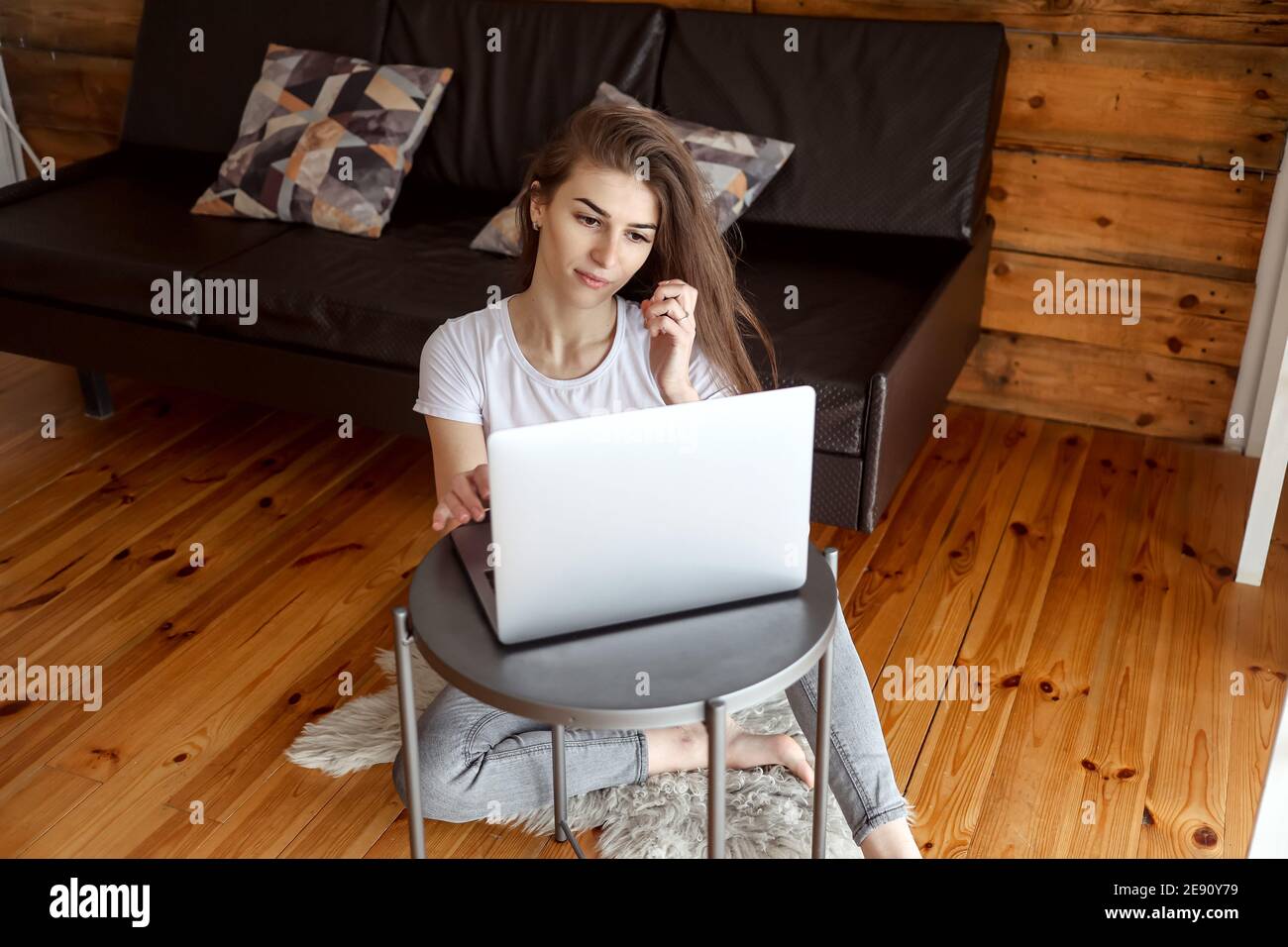 Giovane donna seduta sul pavimento e con un computer portatile. Ragazza allegra trascorrere tempo libero chattando in rete sociale, scrivere messaggio, blogger concentrato fr Foto Stock
