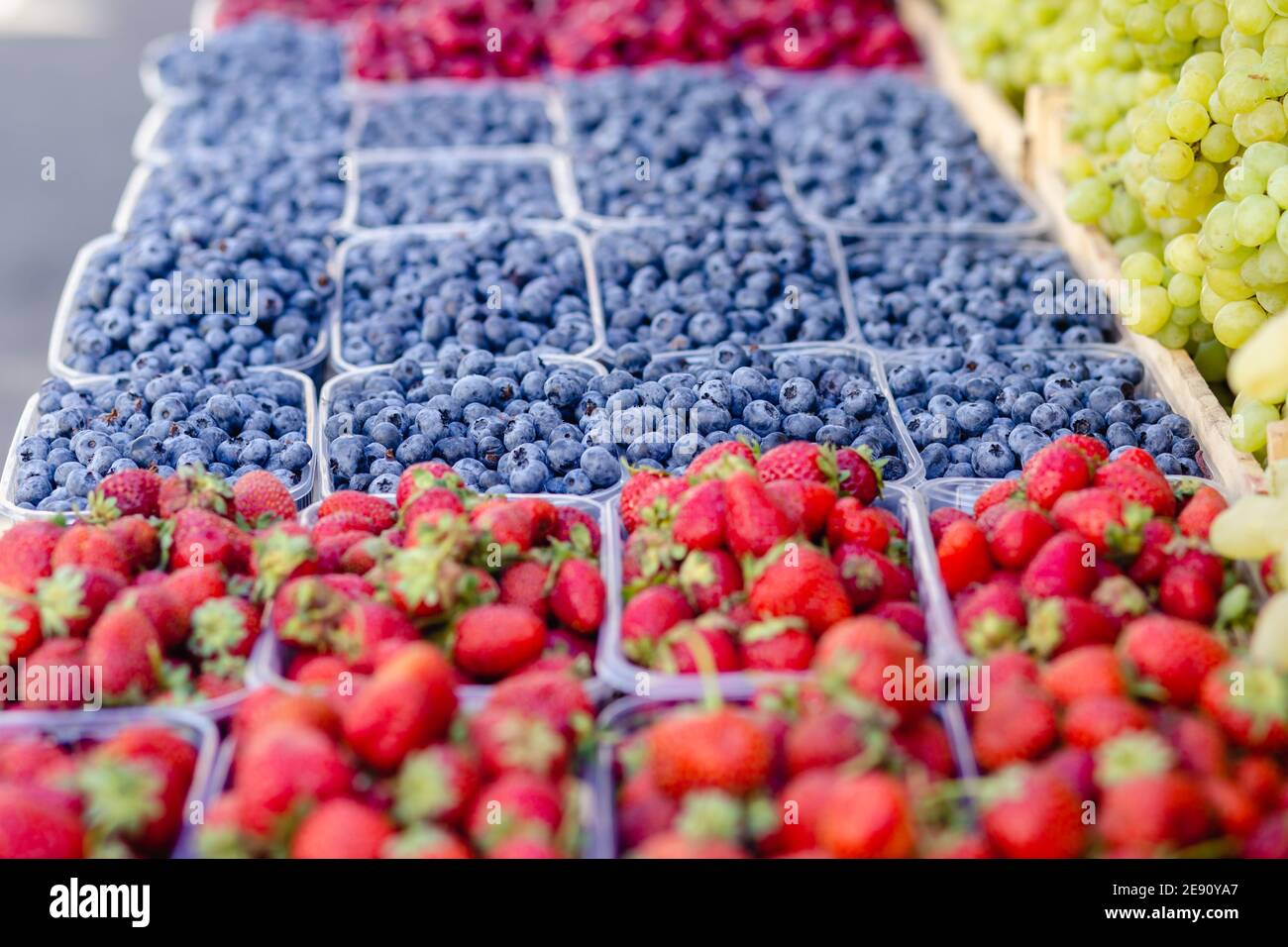 Fragole, lamponi, mirtilli, uva in scatola di plastica trasparente per la vendita allo stand della drogheria sul mercato alimentare. Frutta estiva. H Foto Stock