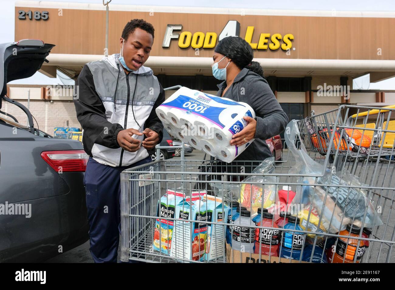 Los Angeles, California, Stati Uniti. 1 febbraio 2021. Gli acquirenti che indossano maschere facciali caricano gli oggetti nel loro veicolo al di fuori di un negozio Food 4 Less, chiuderanno definitivamente il 17 aprile, lunedì 1 febbraio 2021 a Long Beach, California Kroger, Che possiede Ralphs e Food 4 di meno, ha annunciato Lunedi la società chiuderà un Ralphs e un Food 4 di meno a Long Beach in risposta alla decisione della città CouncilÃs di imporre una retribuzione extra 'Hero Pay' per i lavoratori di alimentari in mezzo alla pandemia. Credit: Ringo Chiu/ZUMA Wire/Alamy Live News Foto Stock