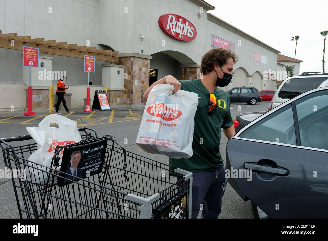 Los Angeles, California, Stati Uniti. 1 febbraio 2021. Un acquirente che indossa una maschera facciale carica gli oggetti nel suo veicolo al di fuori di un negozio Food 4 Less, chiuderà permanentemente il 17 aprile, lunedì 1 febbraio 2021 a Long Beach, California Kroger, Che possiede Ralphs e Food 4 di meno, ha annunciato Lunedi la società chiuderà un Ralphs e un Food 4 di meno a Long Beach in risposta alla decisione della città CouncilÃs di imporre una retribuzione extra 'Hero Pay' per i lavoratori di alimentari in mezzo alla pandemia. Credit: Ringo Chiu/ZUMA Wire/Alamy Live News Foto Stock