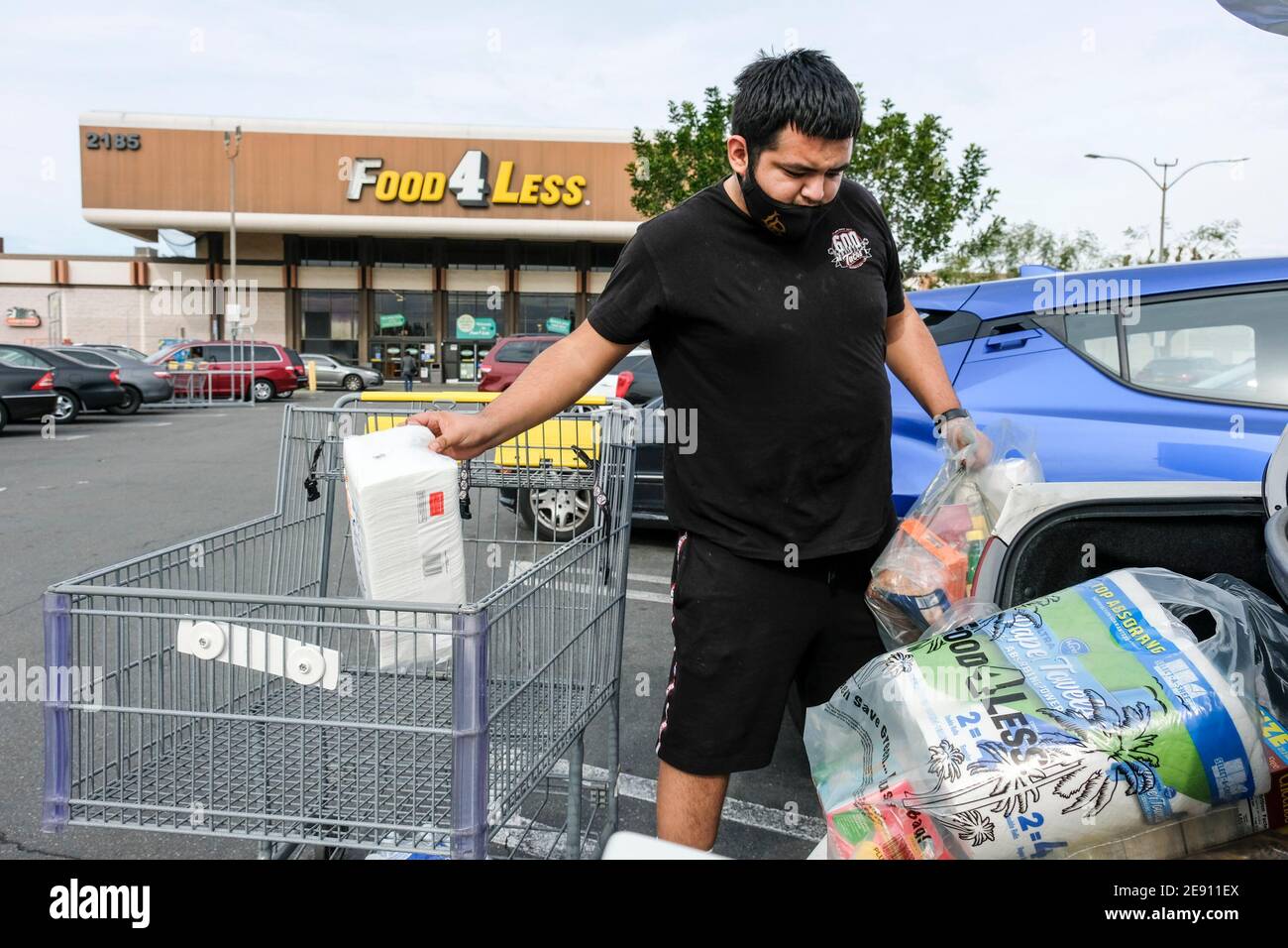 Los Angeles, California, Stati Uniti. 1 febbraio 2021. Un acquirente che indossa una maschera facciale carica gli oggetti nel suo veicolo al di fuori di un negozio Food 4 Less, chiuderà permanentemente il 17 aprile, lunedì 1 febbraio 2021 a Long Beach, California Kroger, Che possiede Ralphs e Food 4 di meno, ha annunciato Lunedi la società chiuderà un Ralphs e un Food 4 di meno a Long Beach in risposta alla decisione della città CouncilÃs di imporre una retribuzione extra 'Hero Pay' per i lavoratori di alimentari in mezzo alla pandemia. Credit: Ringo Chiu/ZUMA Wire/Alamy Live News Foto Stock