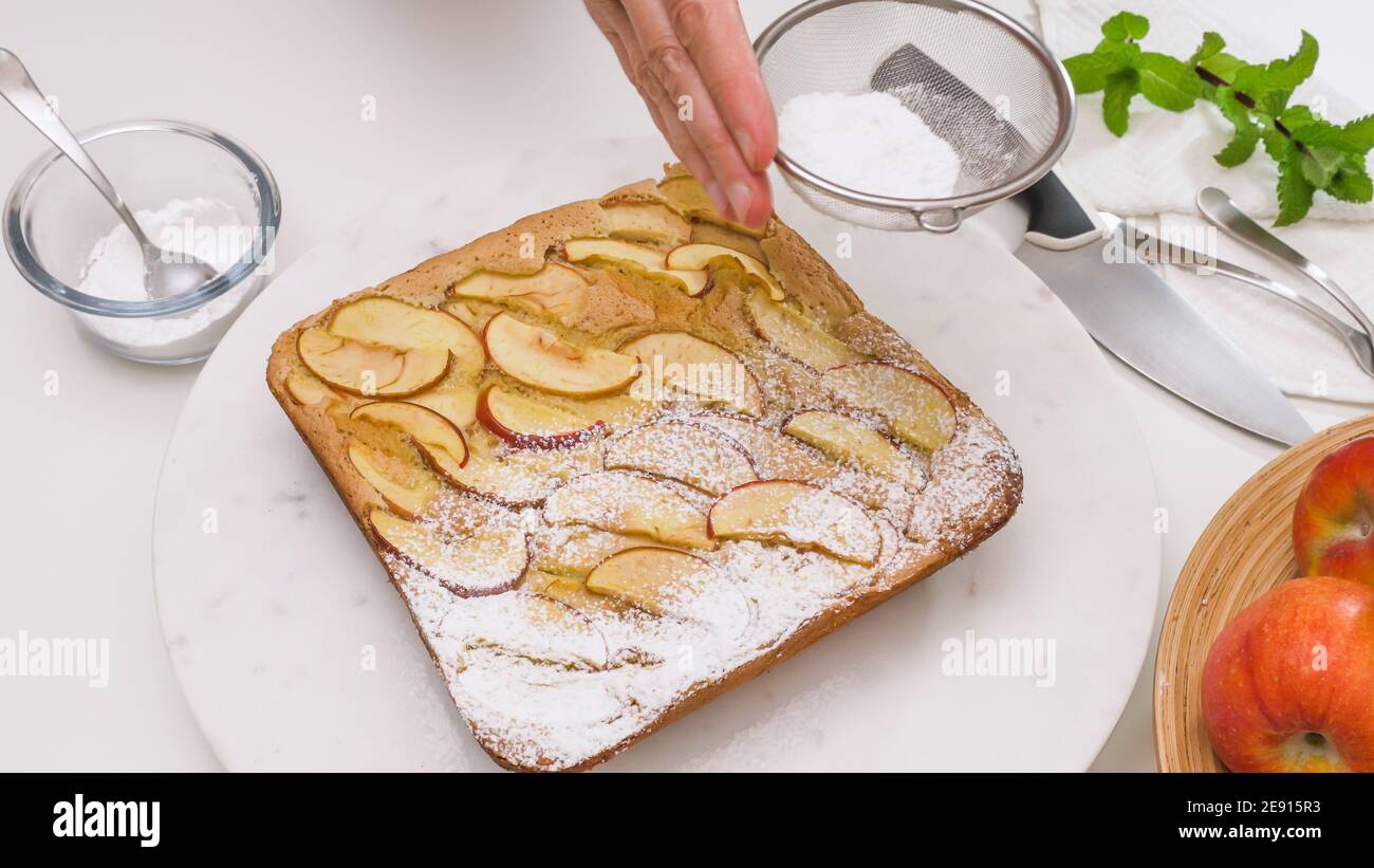 Torta di mele appena sfornata su un tavolo da portata. Condire la torta con zucchero in polvere. Foto Stock