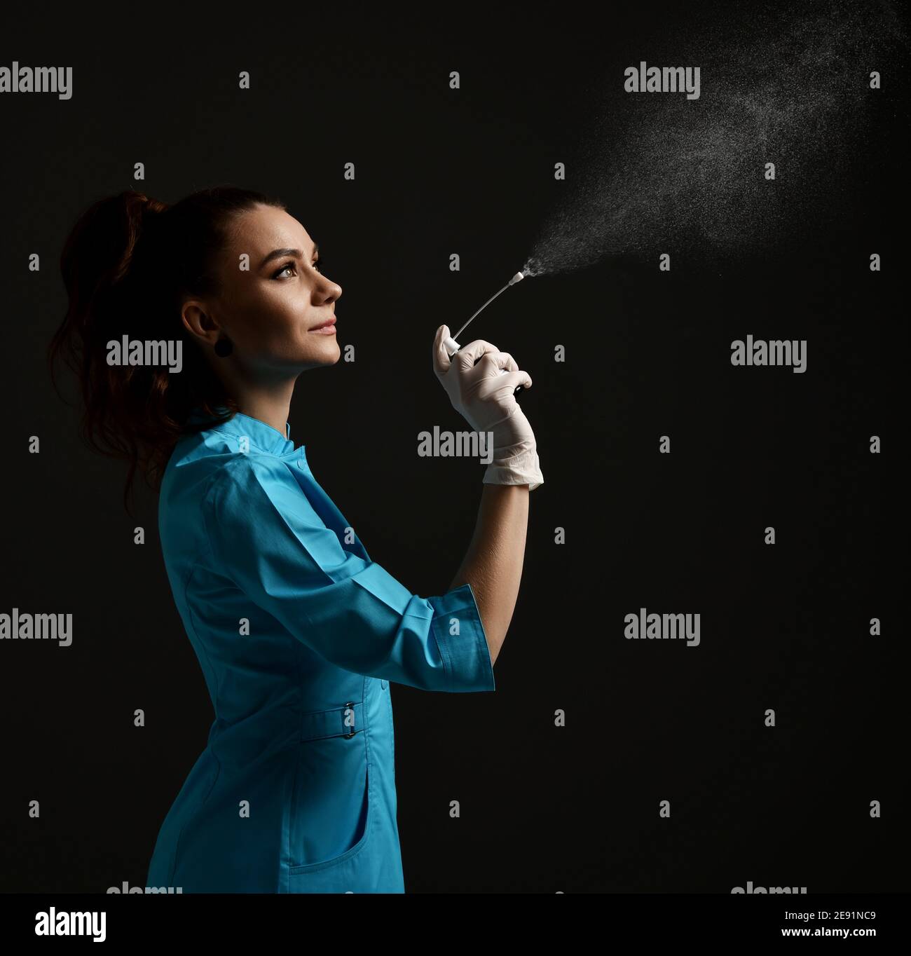 Bella donna brunette medico ginecologo infermiere in guanti di lattice e. abito uniforme per uso medico usa spray disinfettante Foto Stock