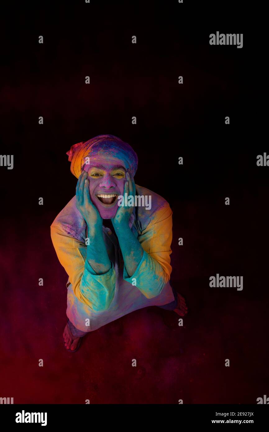 Uomo con un sorriso luminoso sul volto che celebra Holi Foto Stock