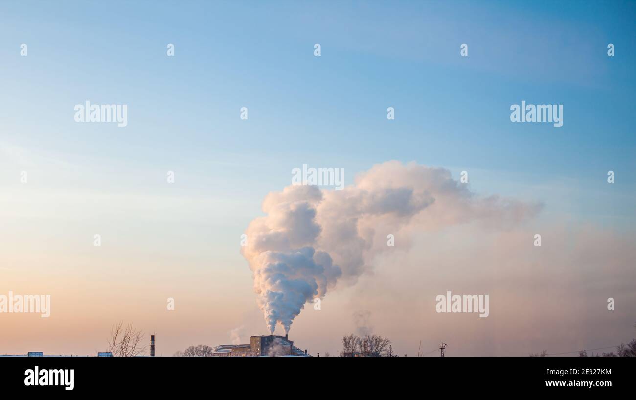 Fumo bianco spesso dal camino del locale caldaia. Fumo contro il cielo blu. Inquinamento atmosferico. Riscaldamento della città. Zona industriale. Foto Stock