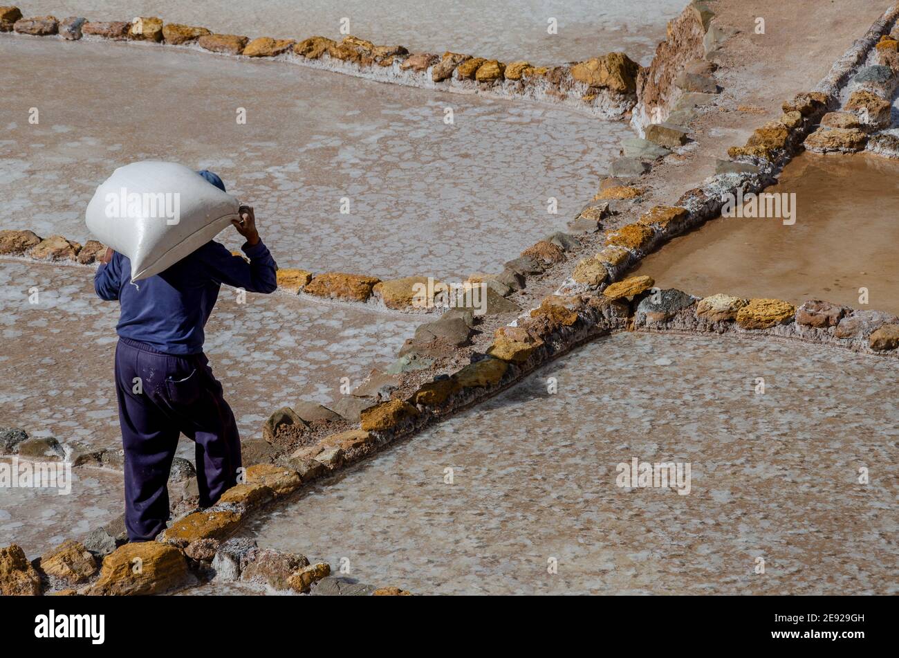 vecchio che porta un sacco enorme di sale su di lui Ritorno a salineras de Maras in Perù Foto Stock