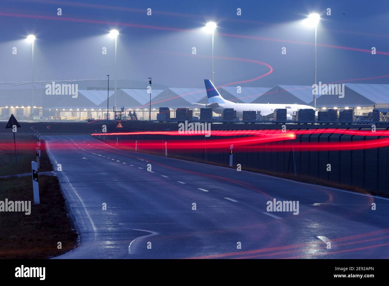 02 febbraio 2021, Sassonia, Schkeuditz: L'auto attraversa i terreni dell'aeroporto di Lipsia/Halle. (Foto a lunga esposizione) l'aeroporto continua a diventare uno dei più importanti centri di trasporto aereo in Europa. Anche se il numero dei passeggeri è diminuito, soprattutto a causa della pandemia di Corona, la portata del carico è aumentata in modo significativo: Nel 2020, è aumentata del 11.7%, raggiungendo appena meno di 1.4 milioni di tonnellate. Solo a dicembre, il trasporto aereo è aumentato del 35%. Grazie a una speciale certificazione, i prodotti farmaceutici sensibili possono essere trattati anche in aeroporto, il che potrebbe quindi svolgere un ruolo importante Foto Stock