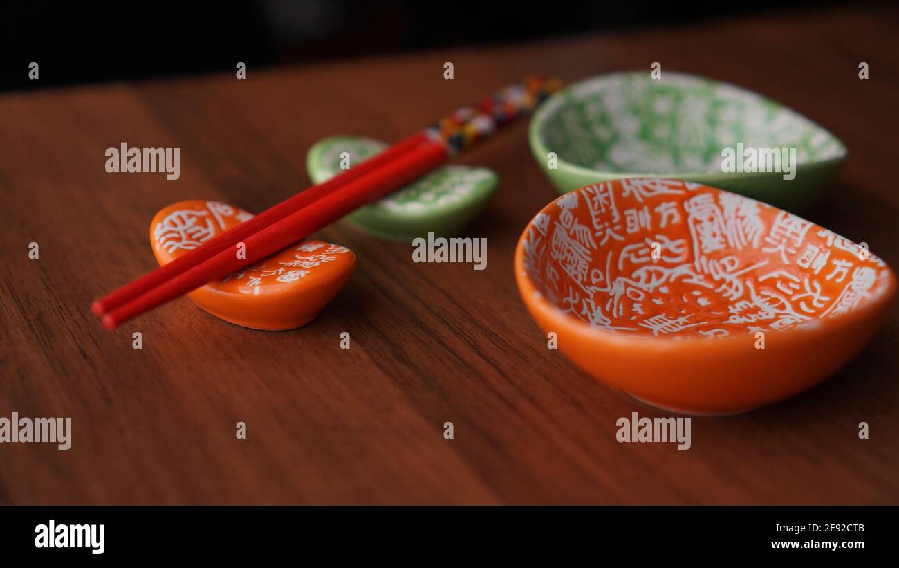 Set di piatti in ceramica per sushi e bastoncini di sushi rosso su sfondo di legno Foto Stock