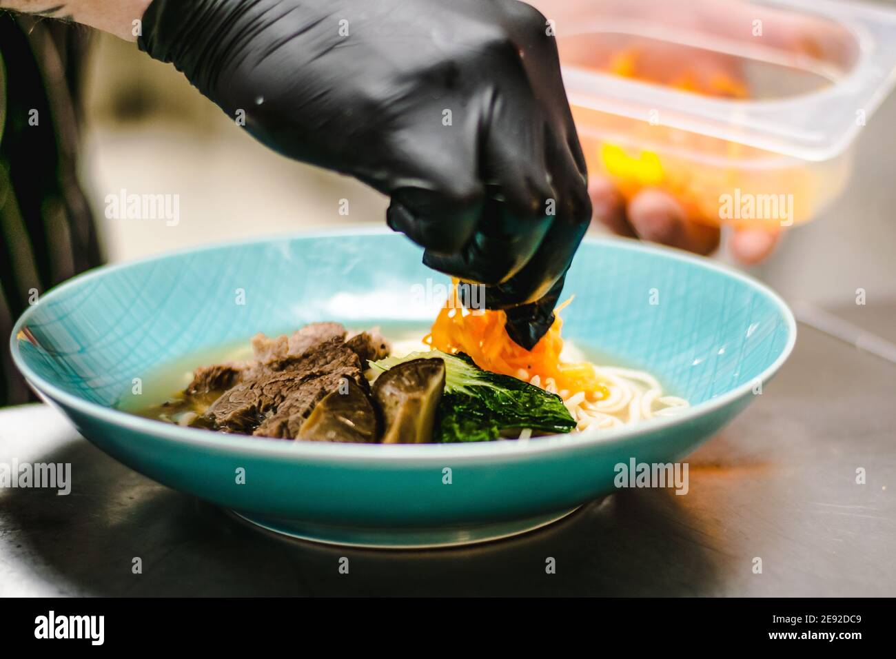 Chef che prepara zuppa di noodle ramen con carne, uova e verdure in un ristorante Foto Stock