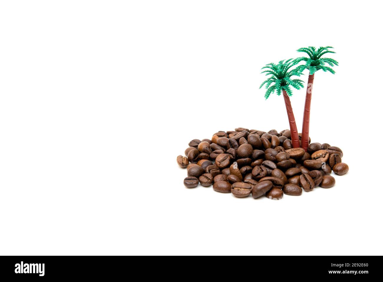 Isola esotica in miniatura fatta di chicchi di caffè torrefatti e palme giocattolo isolate su bianco. Studio shot, spazio per la copia. Foto Stock