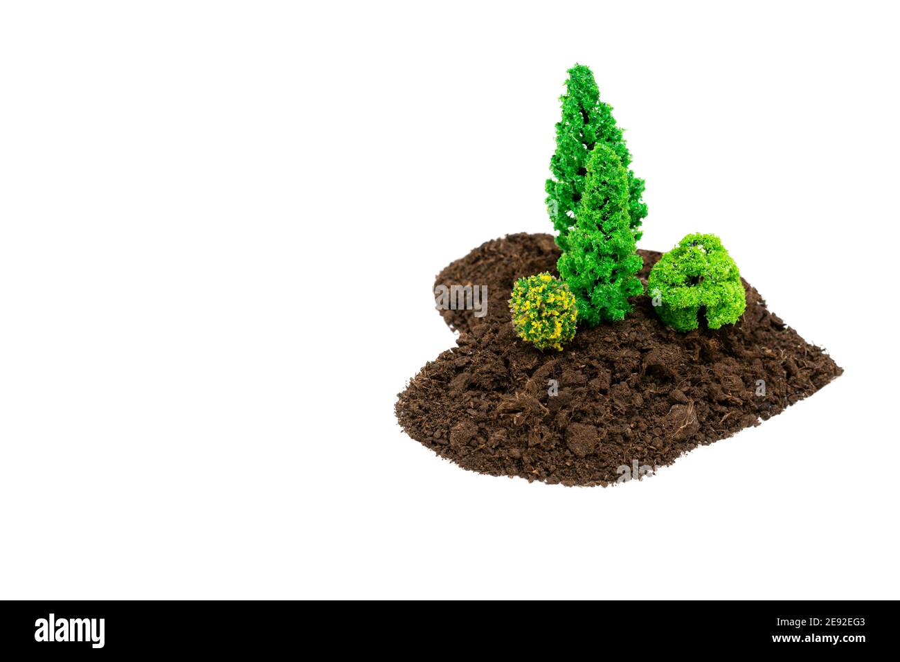 Piccola area forestale a forma di cuore fatta di terreno e giocattolo alberi isolati su bianco Foto Stock