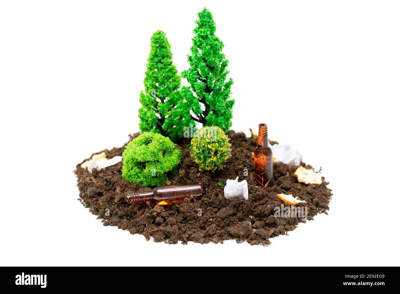 Set di foresta giocattolo in miniatura con un sacco di rifiuti, piccole bottiglie di vetro e carta che giace around.The concetto di mantenere foreste e parchi puliti. Foto Stock