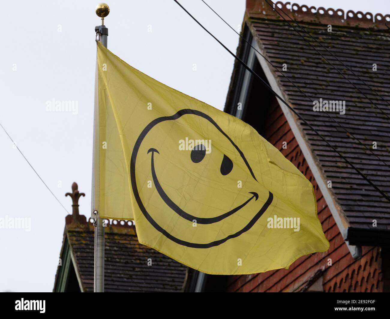 Bandiera gialla con volto smiley che soffia nel vento a Westbury, Wiltshire, Inghilterra, Regno Unito. Foto Stock