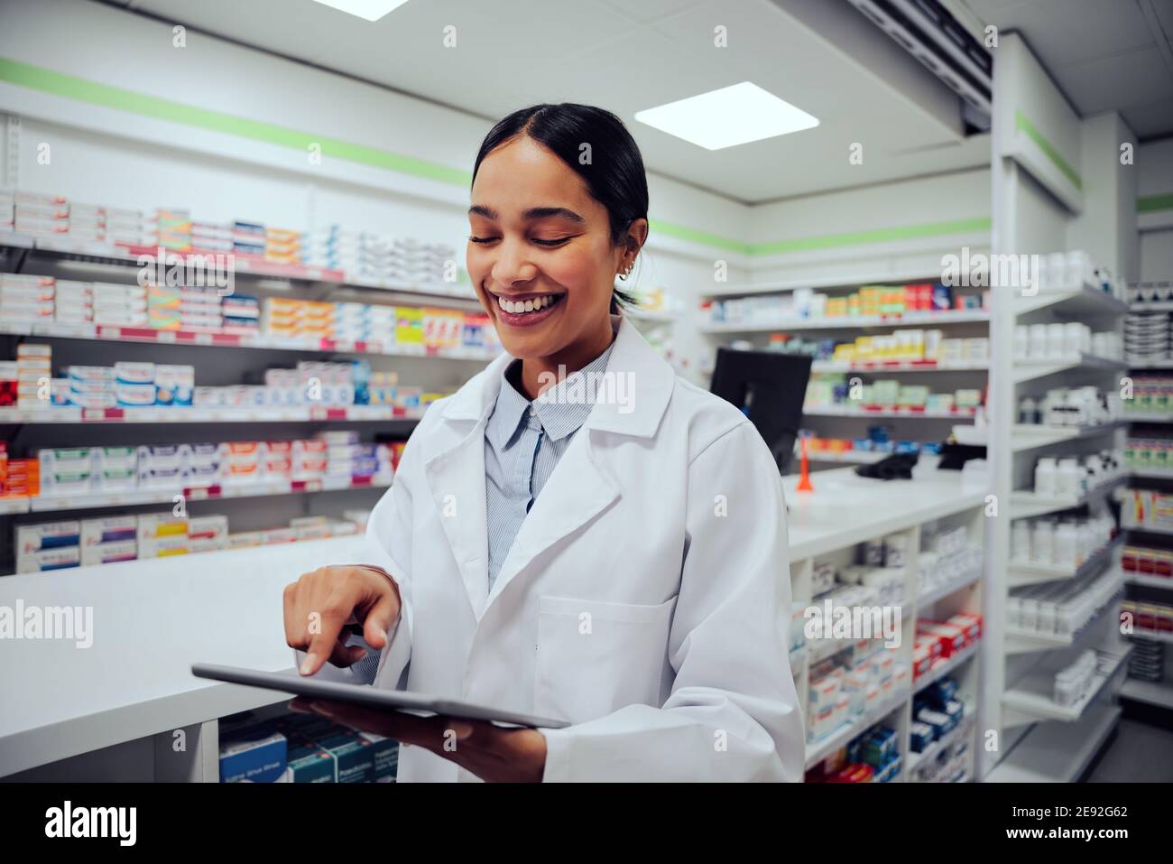 Allegra farmacista femminile utilizzando tablet digitale presso la farmacia dell'ospedale Foto Stock