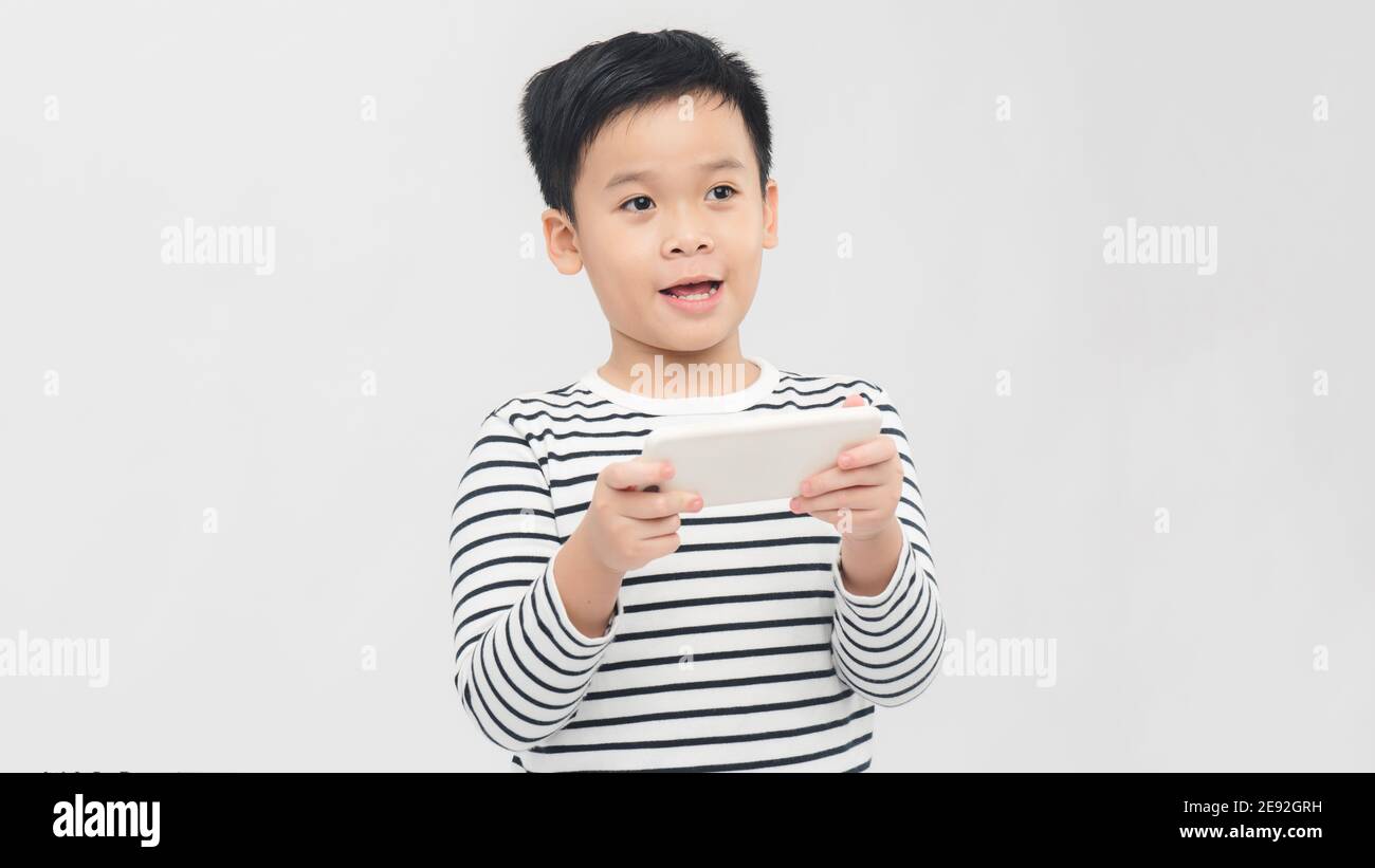 Divertito piccolo ragazzo a giocare su smartphone - posare a. studio Foto Stock