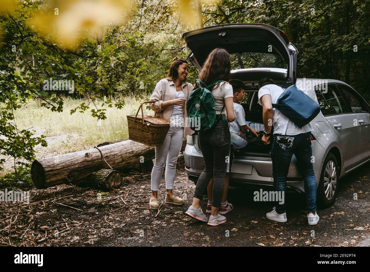 La famiglia rimuove le cose dal tronco dell'automobile nella foresta durante il picnic Foto Stock