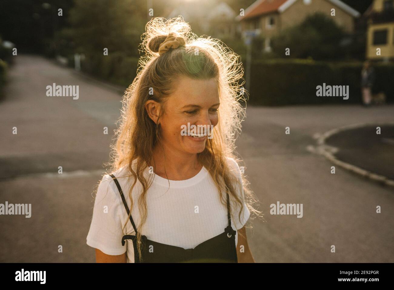 Donna matura sorridente su strada durante il giorno di sole Foto Stock