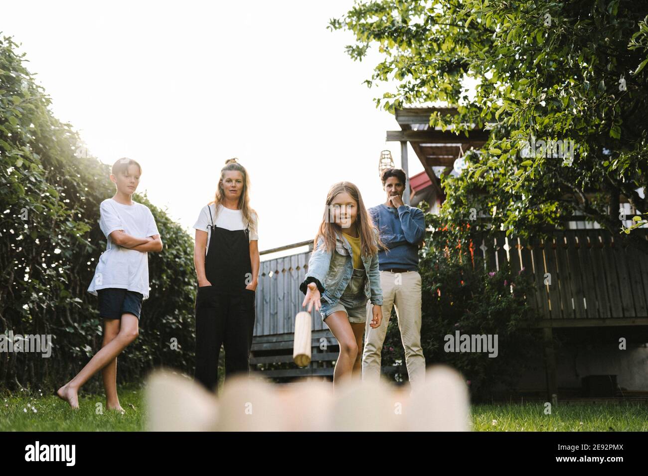 Ragazza che gioca molkky con la famiglia nel cortile posteriore Foto Stock