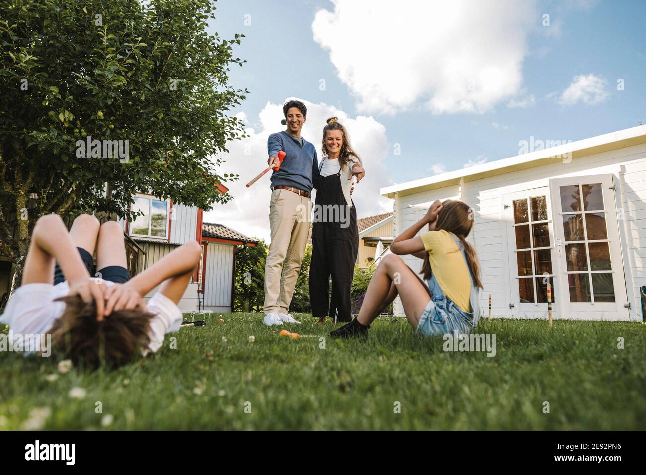 Madre e padre che indicano i bambini nel cortile di fronte Foto Stock