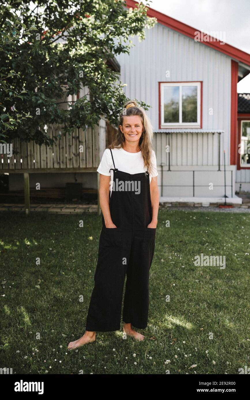 Madre con le mani in tasche in piedi in cortile posteriore Foto Stock