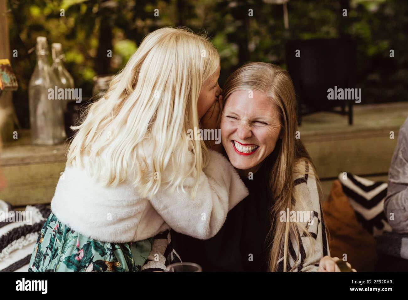 Figlia sussurra qualcosa nell'orecchio della madre Foto Stock