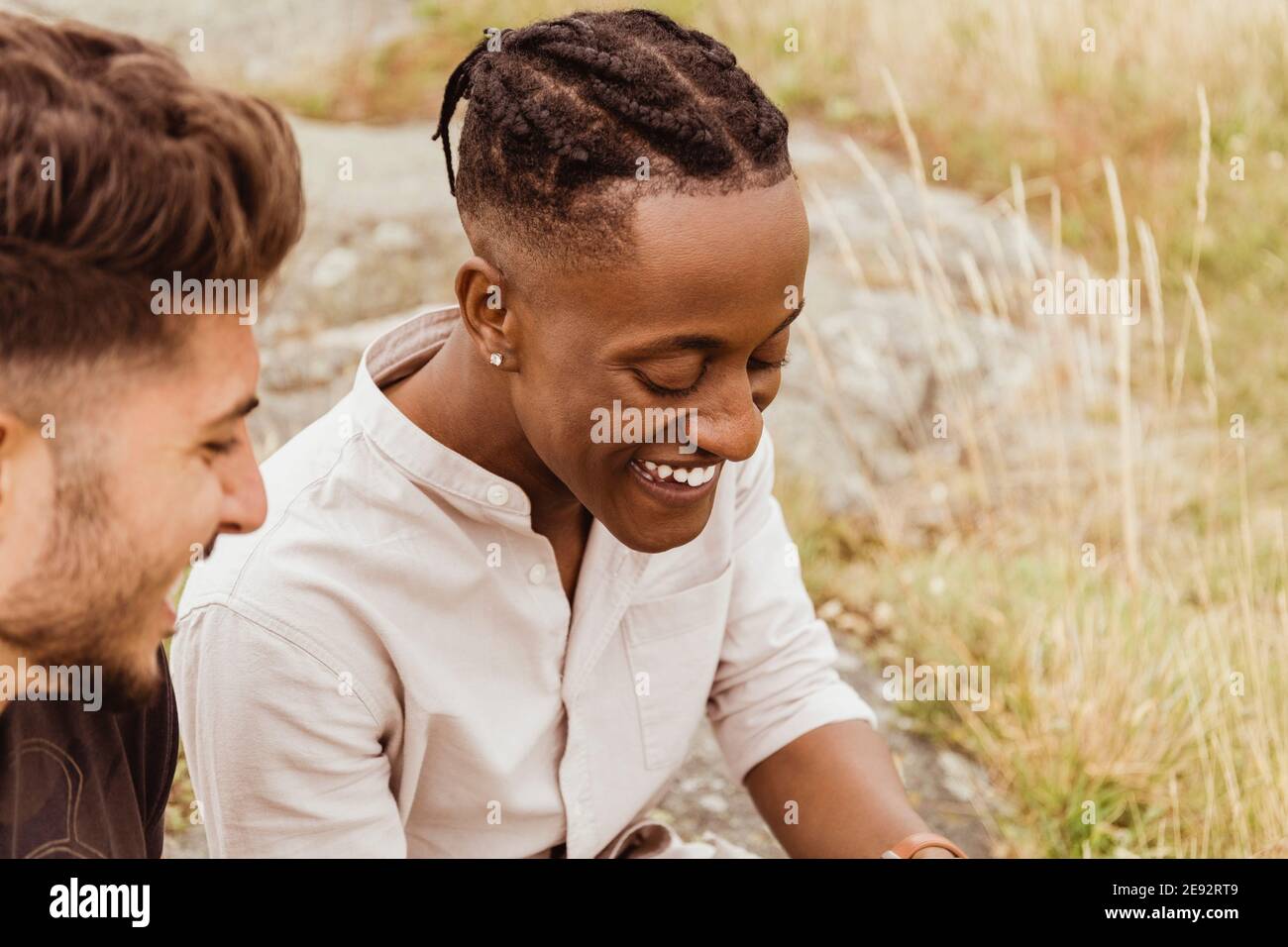 Amici maschi che ridono mentre si siedono all'aperto Foto Stock
