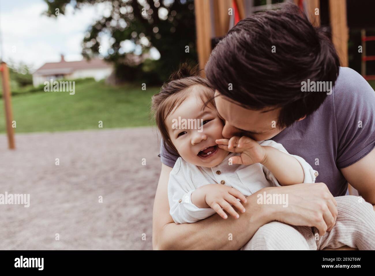 Padre baciando sorridente bambino figlio nel parco Foto Stock