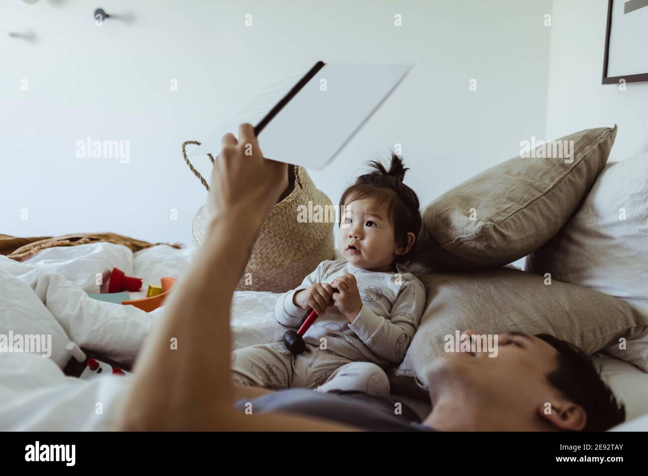 Libro di lettura del padre con il figlio del bambino che si trova sul letto a. casa Foto Stock