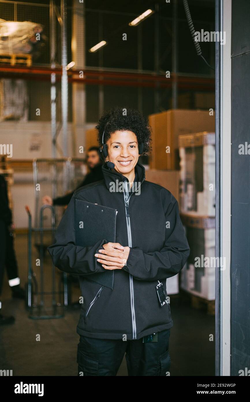 Ritratto di donna imprenditore sorridente con appunti al magazzino di distribuzione Foto Stock