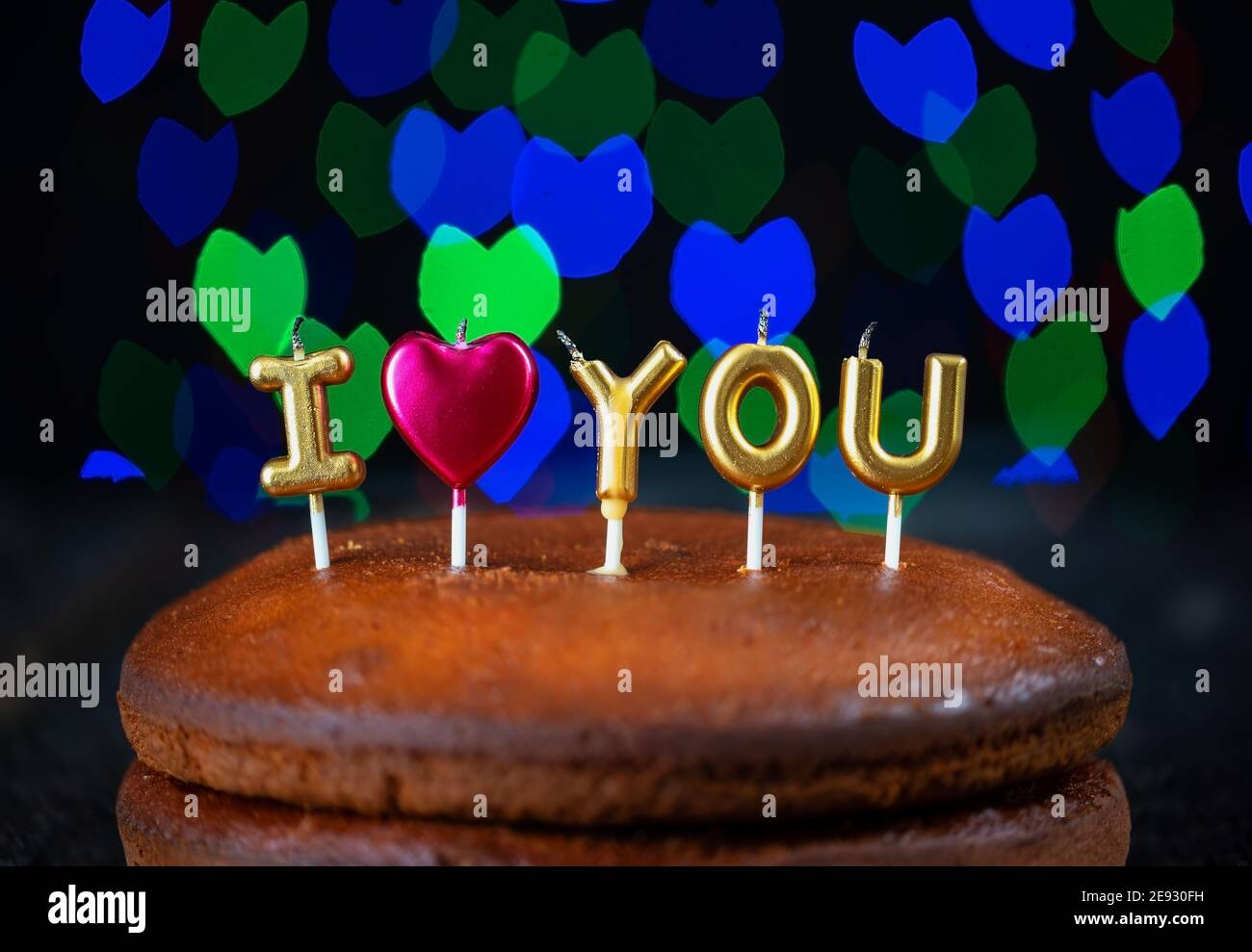 Torta di base con ti amo candele, cuore, posto su un tavolo vintage e bokeh colorati motivi sullo sfondo. Foto Stock