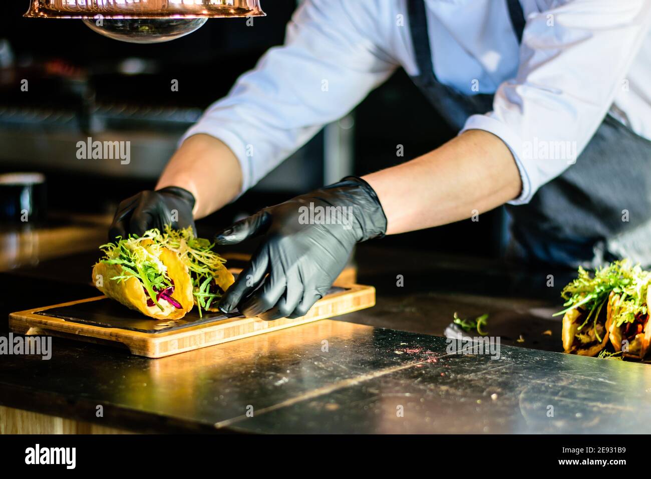 Uno chef che plating tacos in una cucina ristorante Foto Stock