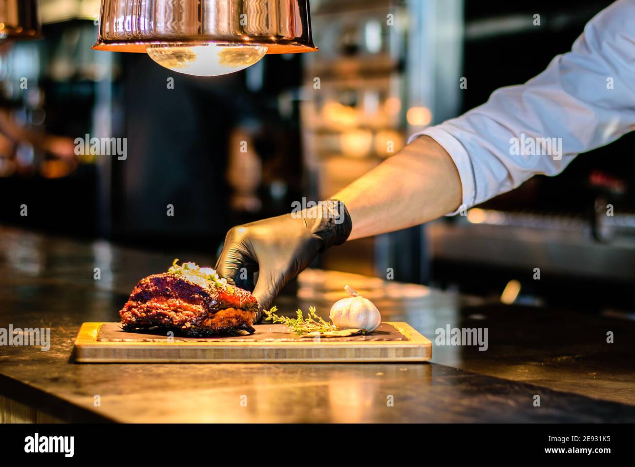 Chef che propone costolette grigliate su un bancone in un ristorante Foto Stock
