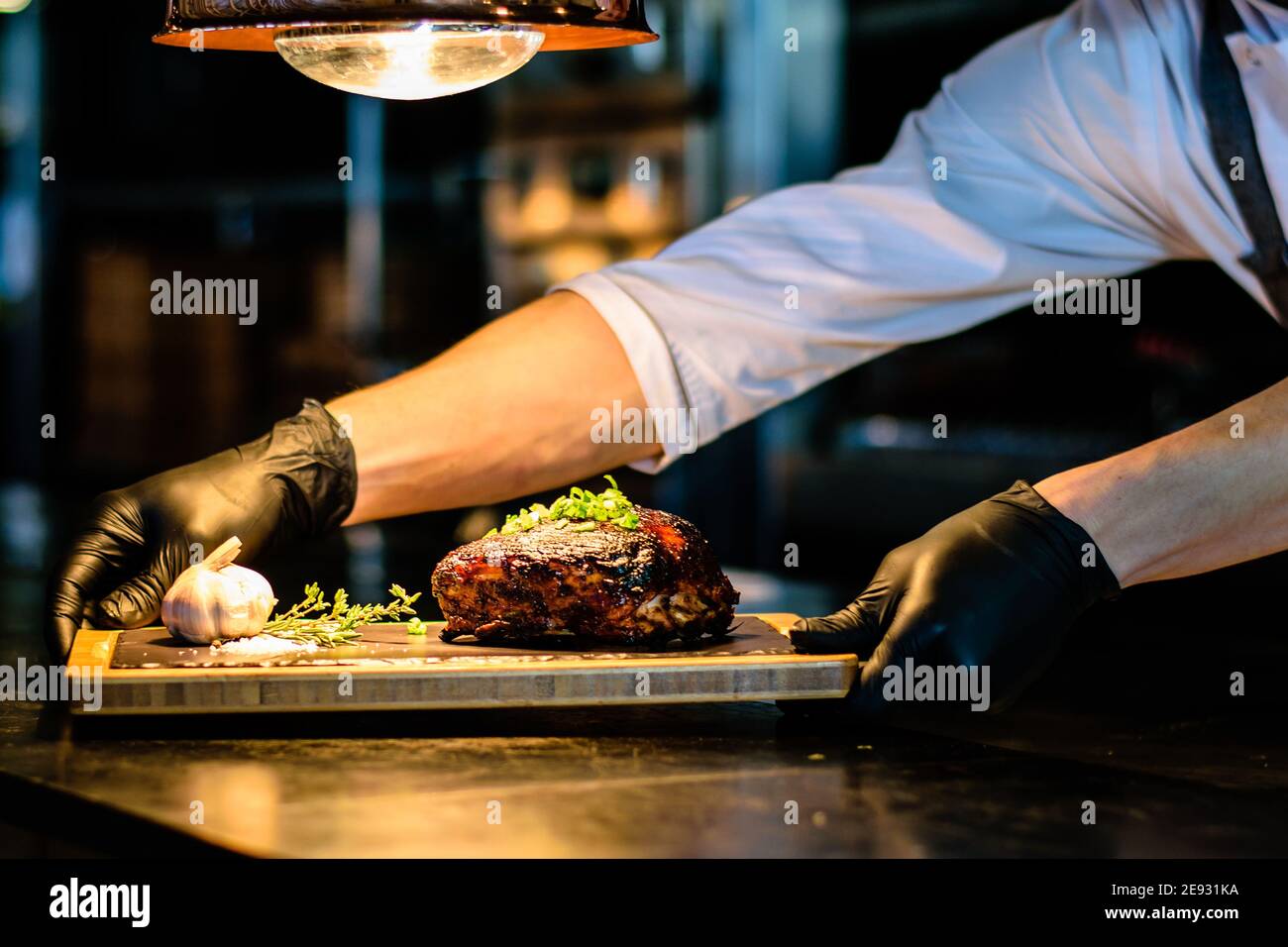 Chef che propone costolette grigliate su un bancone in un ristorante Foto Stock