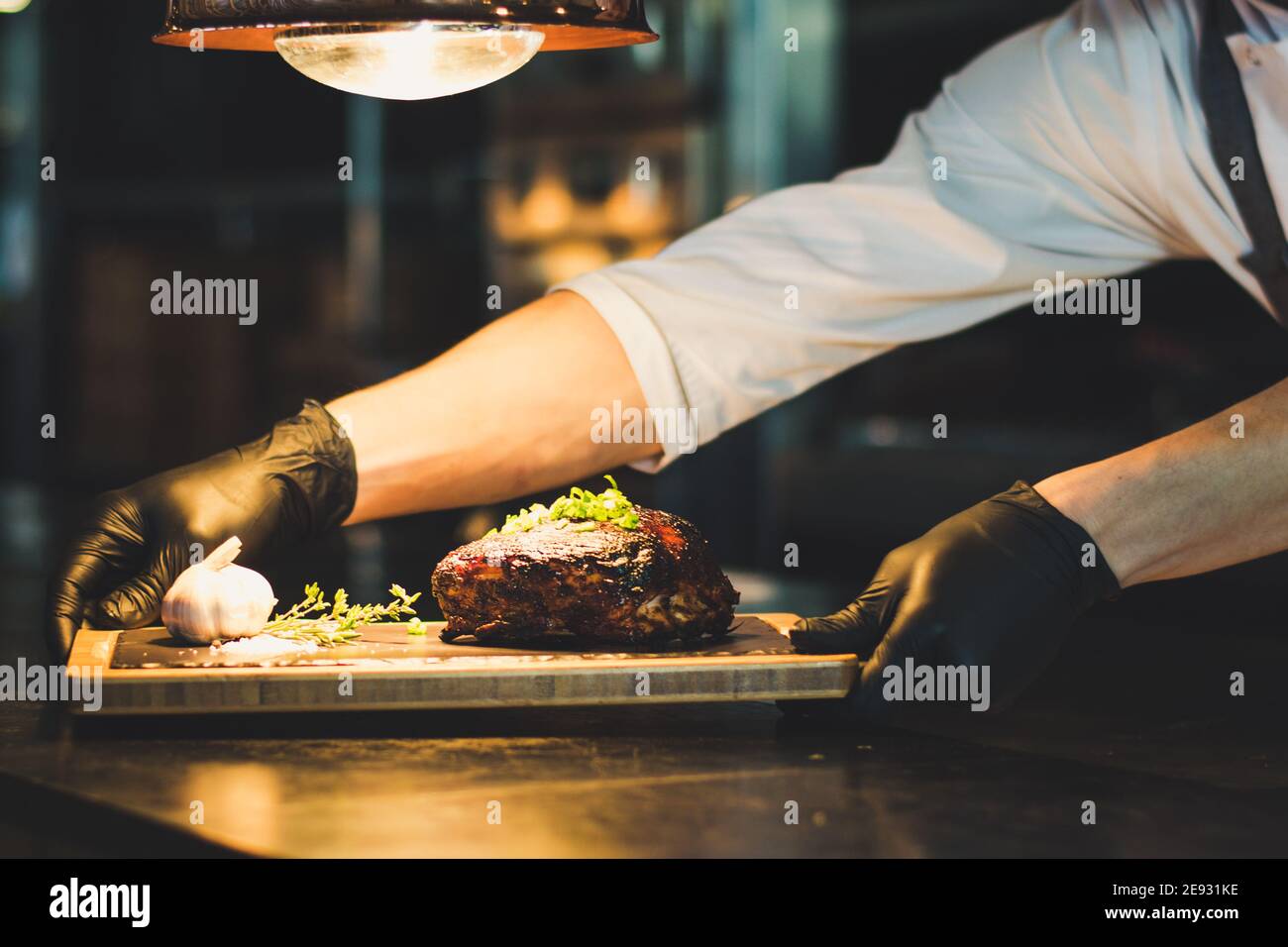 Chef che propone costolette grigliate su un bancone in un ristorante Foto Stock