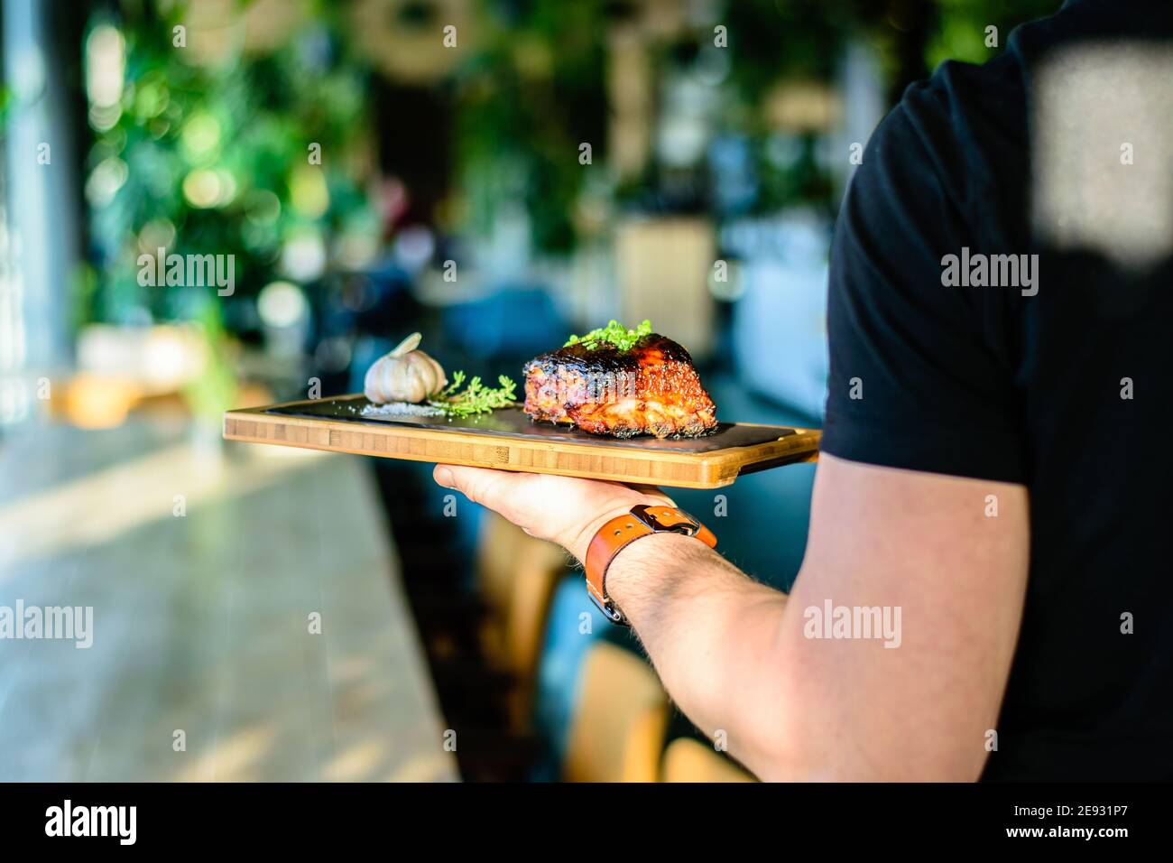 Chef che propone costolette grigliate su un bancone in un ristorante Foto Stock