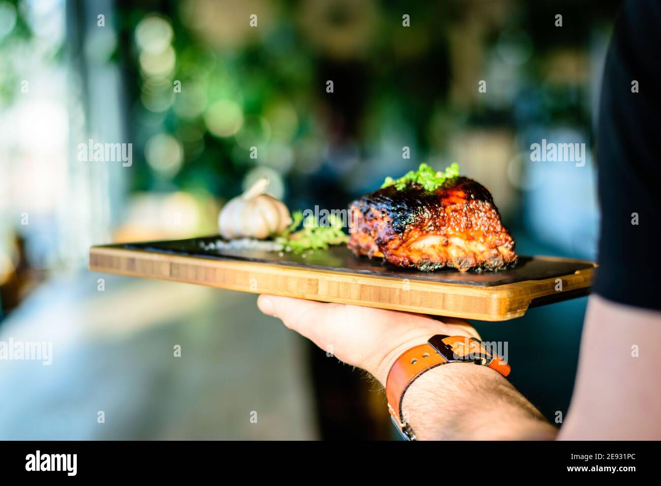 Chef che propone costolette grigliate su un bancone in un ristorante Foto Stock
