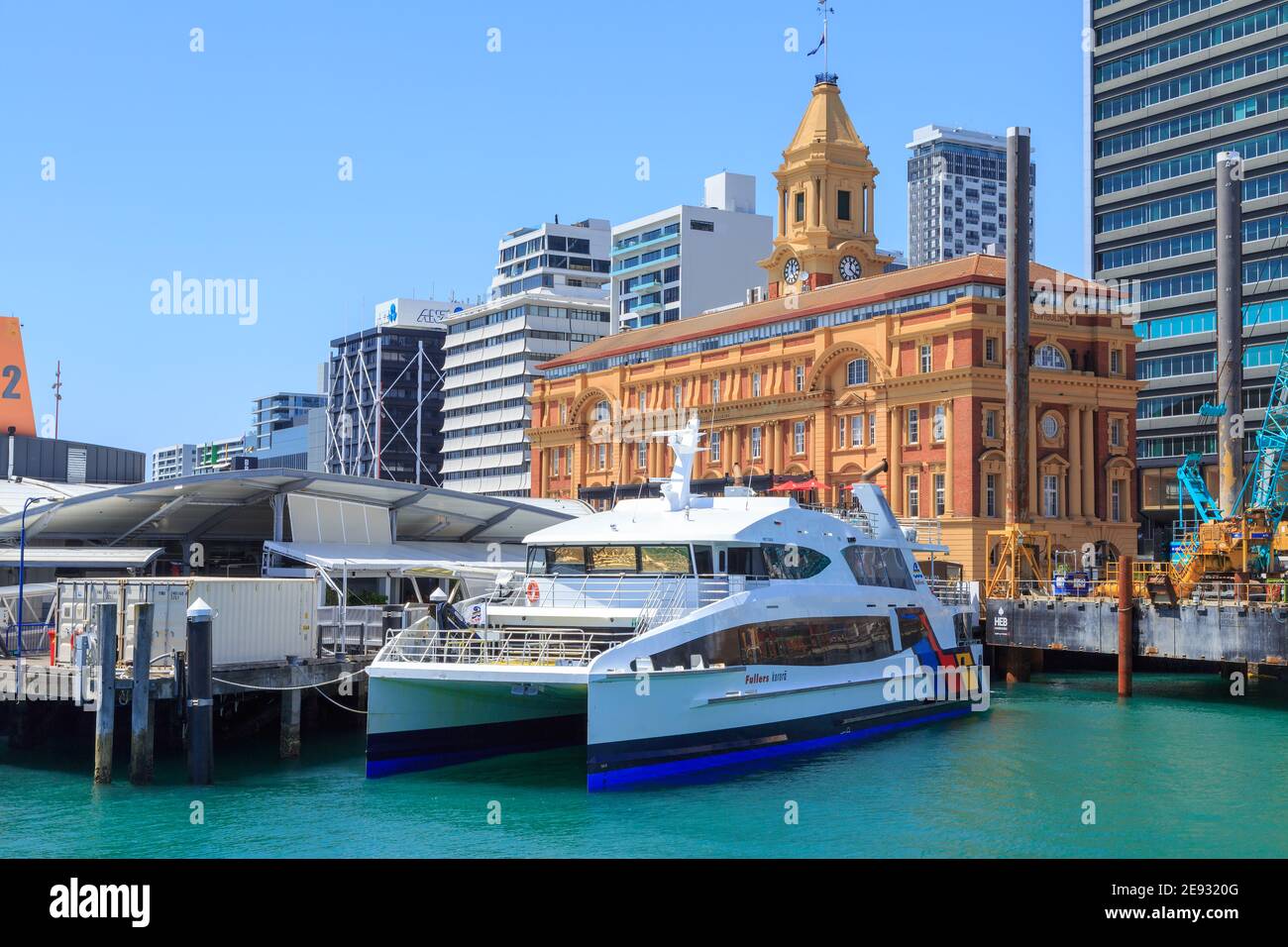 Auckland, Nuova Zelanda. Il moderno traghetto per passeggeri "Korora" si trova di fronte allo storico Ferry Building (1912). Foto Stock