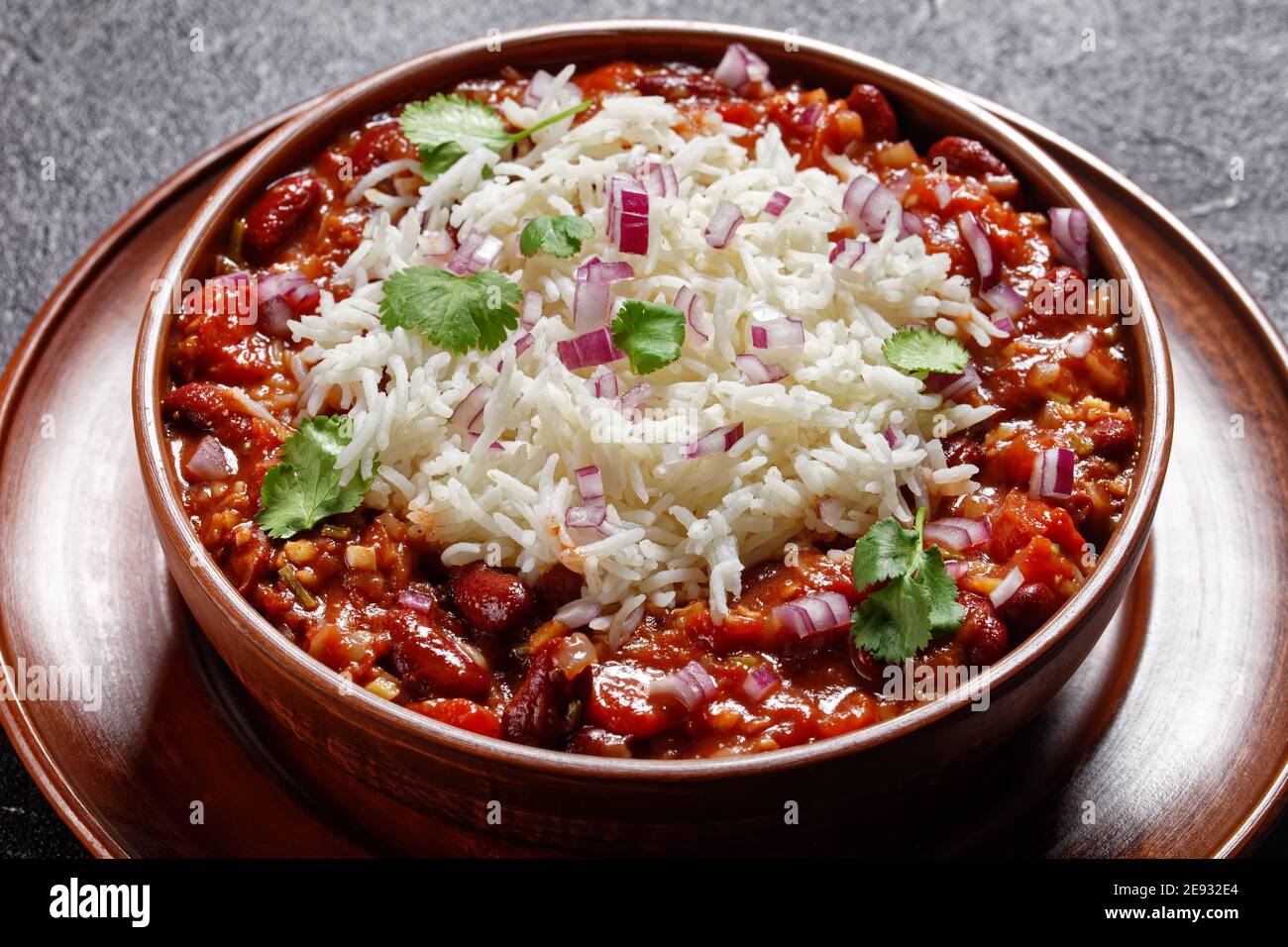 Primo piano di masala di fagiolo rosso di Raja, curry di rene di fagiolo rosso, con riso in una ciotola di argilla su un tavolo di cemento con ingredienti, vista orizzontale dall'alto Foto Stock