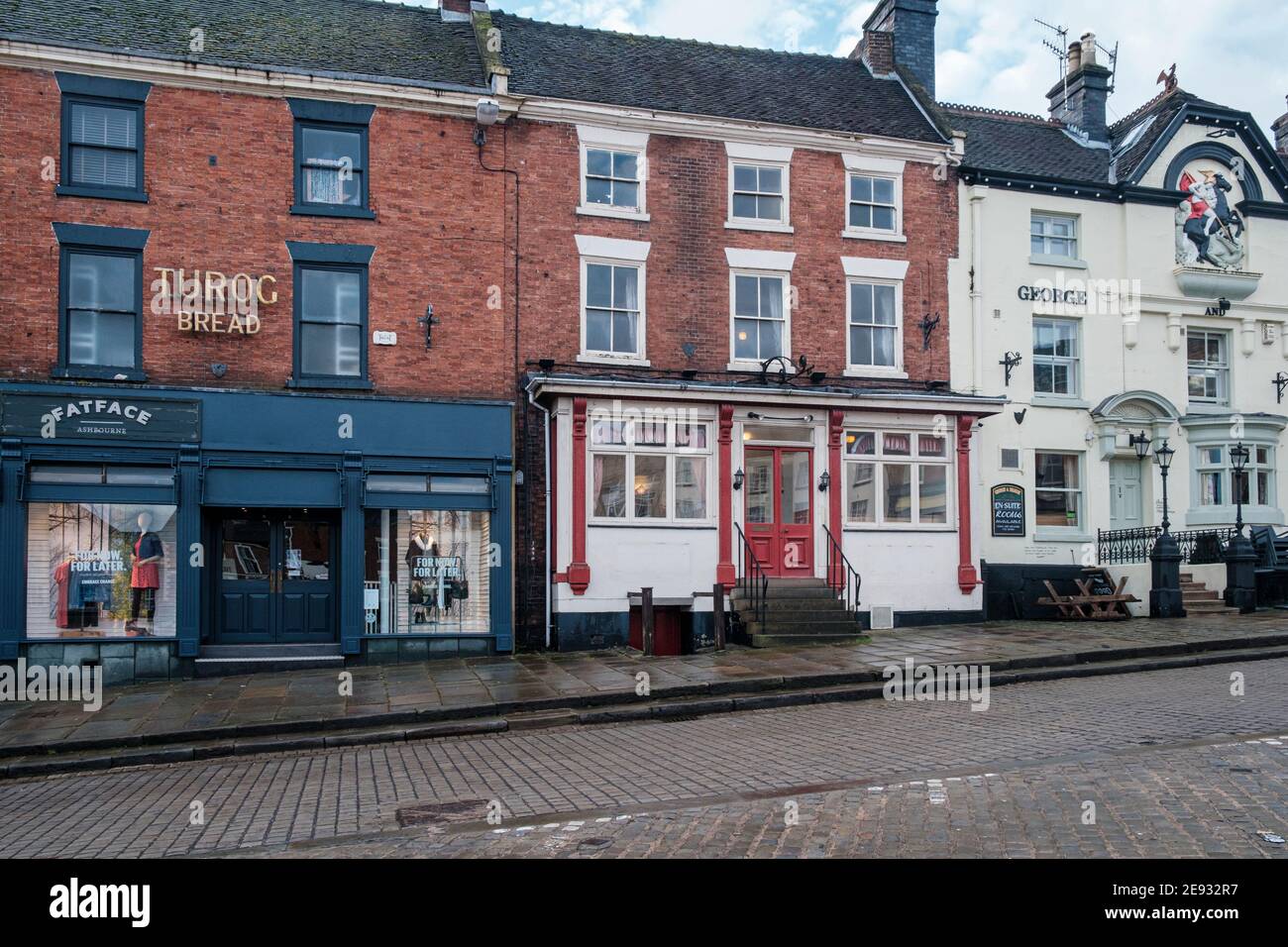 Un vecchio cartello su un ex panificio e sala da tè e edifici georgiani nel mercato, Ashbourne, Derbyshire Foto Stock