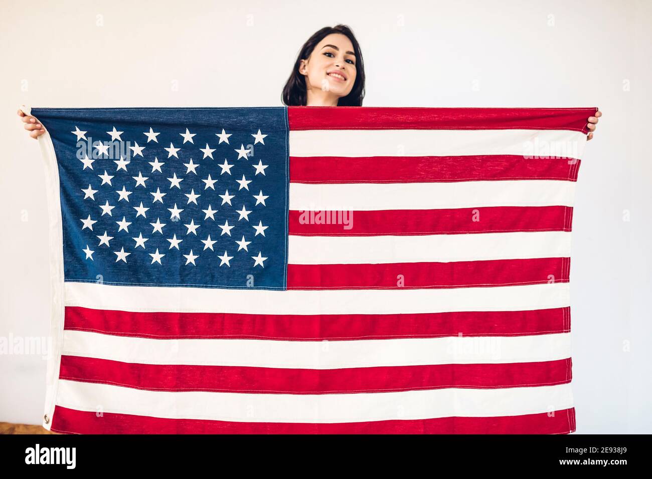 Ritratto di stile di vita di una giovane ragazza felice che tiene una bandiera americana il giorno dell'indipendenza degli Stati Uniti, 4 luglio. Mettere a fuoco la bandiera Foto Stock