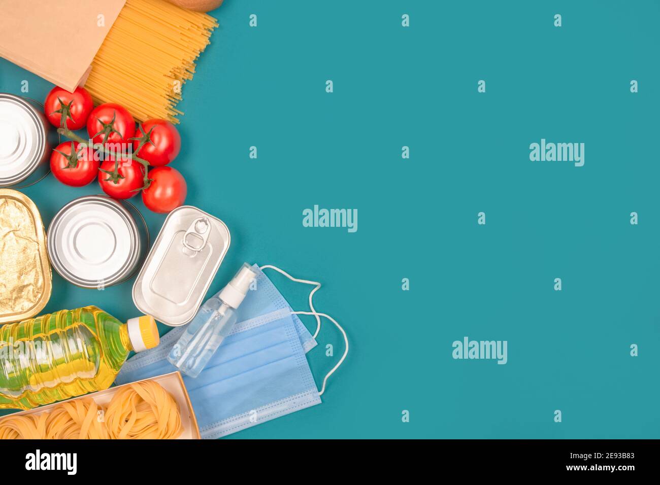 Donazioni di cibo e medicina su sfondo verde con spazio di copia - pasta, verdure fresche, cibo in scatola, baguette, maschera monouso e mano Foto Stock