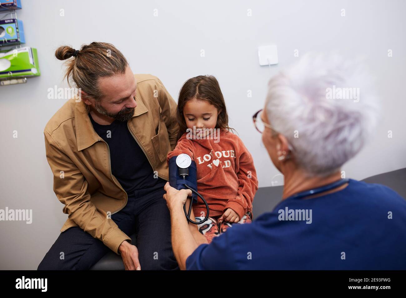 Medico che esamina padre e figlia nel centro di salute Foto Stock
