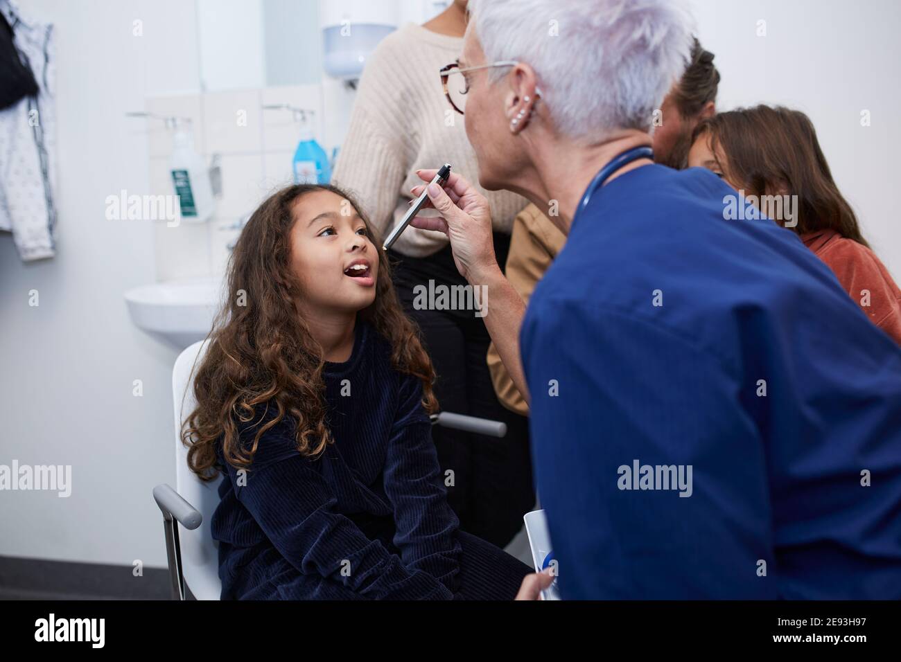 Dottore femminile che controlla la gola delle ragazze Foto Stock