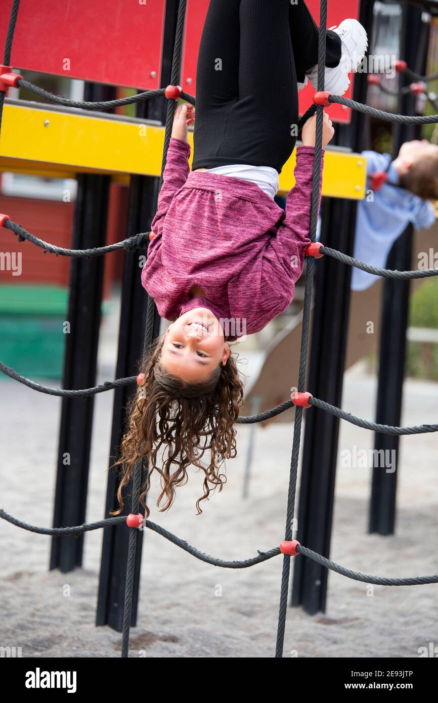 Ragazza che gioca su telaio di arrampicata Foto Stock